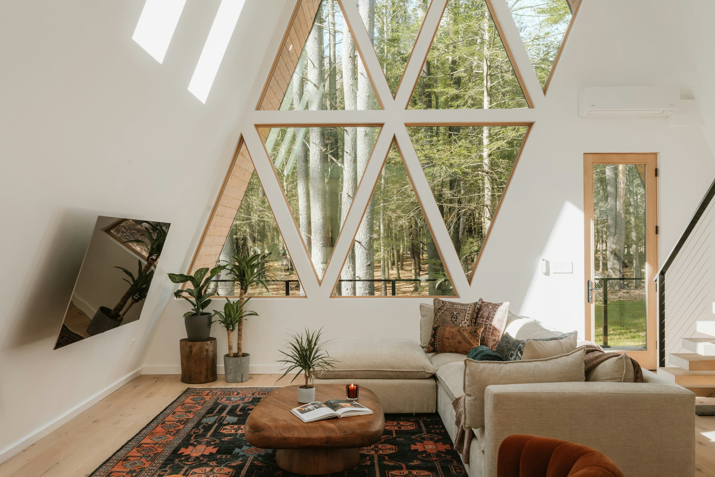 Modern A-frame living room with large windows overlooking the forest